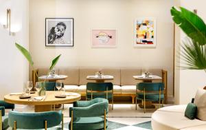 a restaurant with tables and chairs and paintings on the wall at Daios Cove in Agios Nikolaos