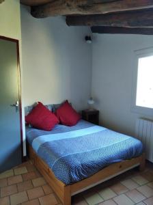 a bedroom with a bed with two red pillows at Gîte en Cévennes in Sumène