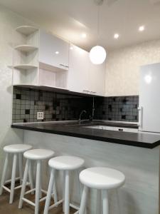 a kitchen with four white stools in front of a counter at Апартаменты in Kirov