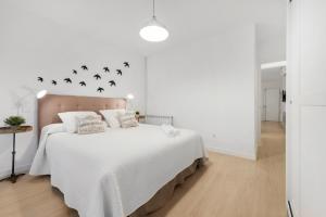 ein weißes Schlafzimmer mit einem großen Bett mit Vögeln an der Wand in der Unterkunft MintyStay - Luca de Tena in Madrid