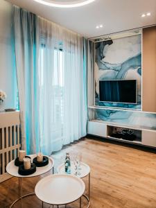 a living room with two tables and a tv at Oceana Silesian Place Apartments in Katowice
