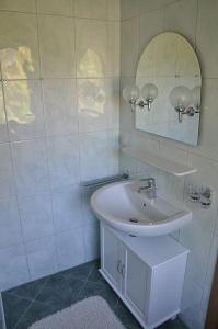 a white bathroom with a sink and a mirror at Ferienhaus Blüthner in Grube