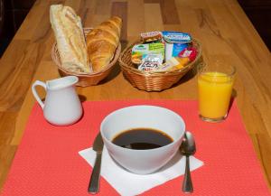 uma mesa com uma chávena de café, pão e sumo em Hôtel Mac Bed em Poitiers