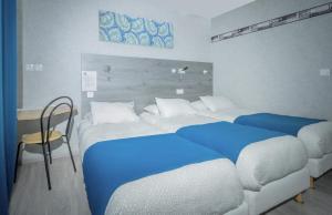 a bedroom with two beds with blue sheets and a desk at Hôtel Mac Bed in Poitiers