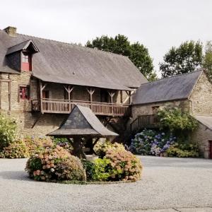 a large stone building with a bridge and flowers at Domaine de La Gaudinais in Ploërmel
