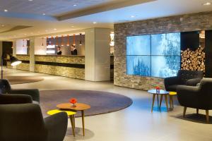 a lobby with a large tv and chairs and tables at Heliopic Hotel & Spa in Chamonix