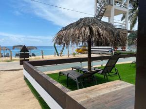 patio con tavolo, sedie e ombrellone di paglia di The Barat Tioman Beach Resort a Kampong Juara