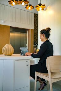 a woman sitting at a desk with a laptop at Live Hotels Bordeaux Lac in Bordeaux