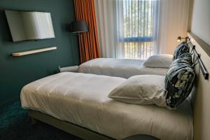 a hotel room with two beds and a television at Live Hotels Bordeaux Lac in Bordeaux
