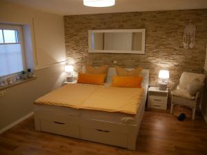 a bedroom with a bed with orange pillows and a brick wall at Haus Alexandra in Schwarzenbach an der Saale