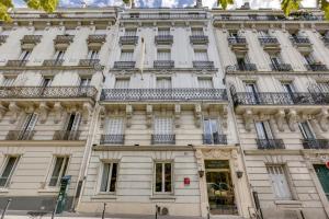 a large white building with balconies on a street at Hôtel du Square d'Anvers in Paris