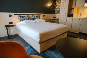 a bedroom with a large bed and a table at Live Hotels Bordeaux Lac in Bordeaux