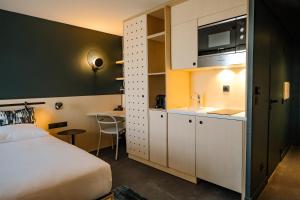 a hotel room with a bed and a kitchen with a sink at Live Hotels Bordeaux Lac in Bordeaux