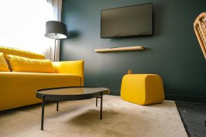 a living room with a yellow couch and a table at Live Hotels Bordeaux Lac in Bordeaux