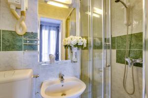 a bathroom with a sink and a shower with a vase of flowers at Hôtel du Square d'Anvers in Paris