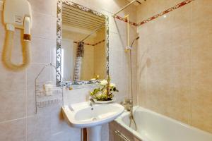 a bathroom with a sink and a mirror and a tub at Hôtel du Square d'Anvers in Paris