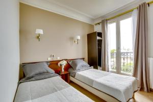 two beds in a room with a window at Hôtel du Square d'Anvers in Paris