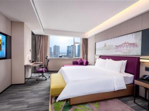 a hotel room with a large bed and a desk at Hampton by Hilton Qinhuangdao Jinmeng Bay in Qinhuangdao