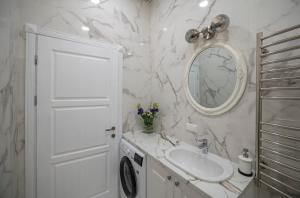 een witte badkamer met een wastafel en een spiegel bij Botanical garden apartment in Kaunas +10 foto's