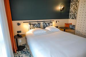 a bedroom with a large white bed and two tables at Live Hotels Bordeaux Lac in Bordeaux