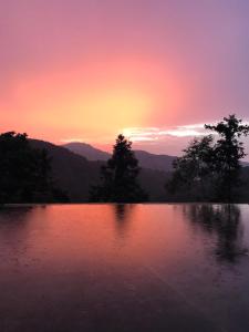 a sunset over a lake with trees and mountains at Bliss Bed and Breakfast in Yuchi