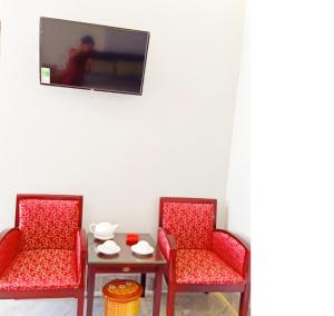 2 sillas y mesa con TV en la pared en HOTEL DUY NHẤT, en Phú Nhơn