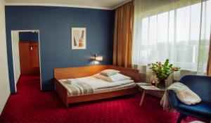 ein Schlafzimmer mit einem Bett und einer blauen Wand in der Unterkunft Hotel Albatros in Przemyśl