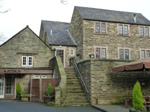 an old stone house with a stone staircase in front at The Manor House Hotel in Dronfield