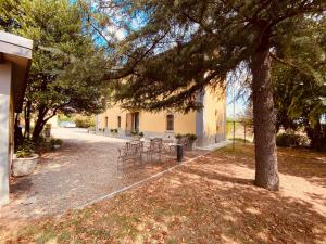 eine Gruppe von Stühlen unter einem Baum neben einem Gebäude in der Unterkunft B&B Villino Margherita in San Lazzaro di Savena