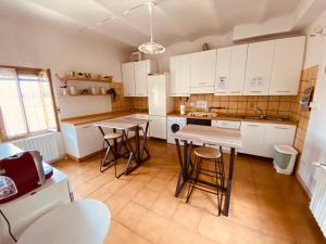 una cocina con armarios blancos, mesa y taburetes en B&B Villino Margherita, en San Lazzaro di Savena