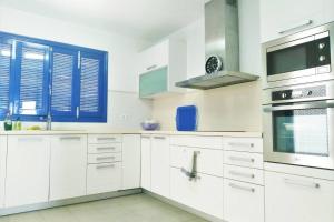 a white kitchen with white cabinets and a blue window at Auténtica Casa Mediterránea con vistas al mar in Santa Pola
