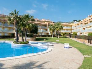 a large apartment building with a swimming pool and palm trees at Residencial Sierra de Irta in Alcossebre