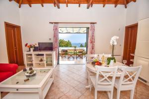 Corfu Resorts Villas في بيليكاس: غرفة معيشة مع طاولة وكراسي وغرفة طعام