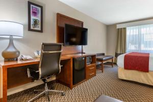 a hotel room with a desk with a television and a bed at Comfort Suites Phoenix Airport in Tempe