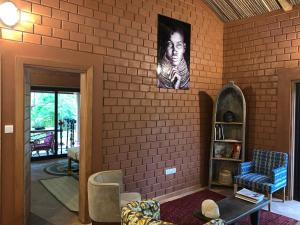 a room with a brick wall with a picture of a woman at Natura luxury red house in Ouidah