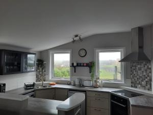 una cocina con fregadero y 2 ventanas. en River Shack, en Doolin