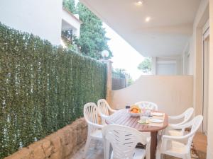 une table et des chaises sur une terrasse avec une haie dans l'établissement Apartamentos Marineu Cala Gonzalez, à Alcossebre