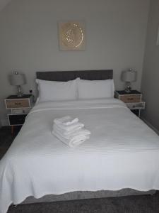 un letto bianco con tre asciugamani sopra di River Shack a Doolin