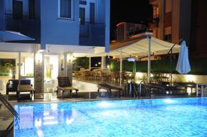 a swimming pool with tables and chairs and an umbrella at Afsin Hotel in Antalya