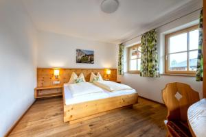 a bedroom with a wooden bed and two windows at Gästehaus Rass in Lofer