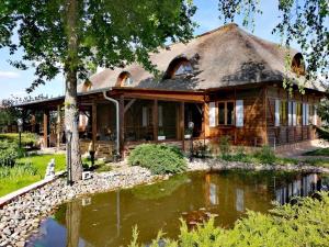 a log house with a pond in front of it at Hotel Zasieki in Zasieki