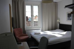 1 dormitorio con 1 cama, 1 silla y 1 ventana en Grännagården, en Gränna