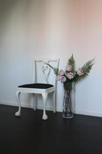 una sedia bianca e un vaso di fiori accanto a una sedia di Grännagården a Gränna