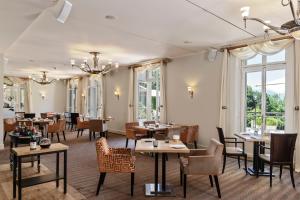 een restaurant met tafels, stoelen en ramen bij Hôtel Résidence Parc des Eaux Vives in Genève