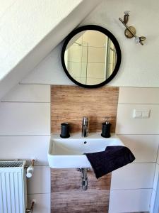 La salle de bains est pourvue d'un lavabo blanc et d'un miroir. dans l'établissement GP Ferienwohnung, à Goslar