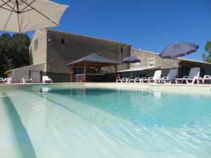 Junas的住宿－Domaine de Christin Studios-Hôtel，一个带椅子和遮阳伞的大型游泳池