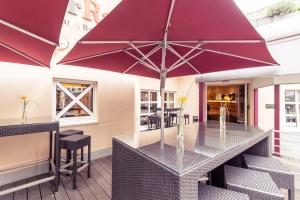 een tafel met een grote paarse parasol op een patio bij Mercure Hotel Köln City Friesenstraße in Keulen