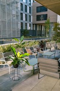 un patio con mesas, sillas y edificios en Live Hotels Bordeaux Lac en Burdeos