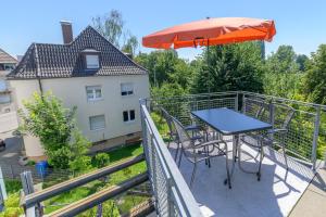 - un balcon avec une table et un parasol dans l'établissement Stadthaus Seeblick E75, à Friedrichshafen