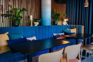 a dining room with two tables and a blue couch at Live Hotels Bordeaux Lac in Bordeaux